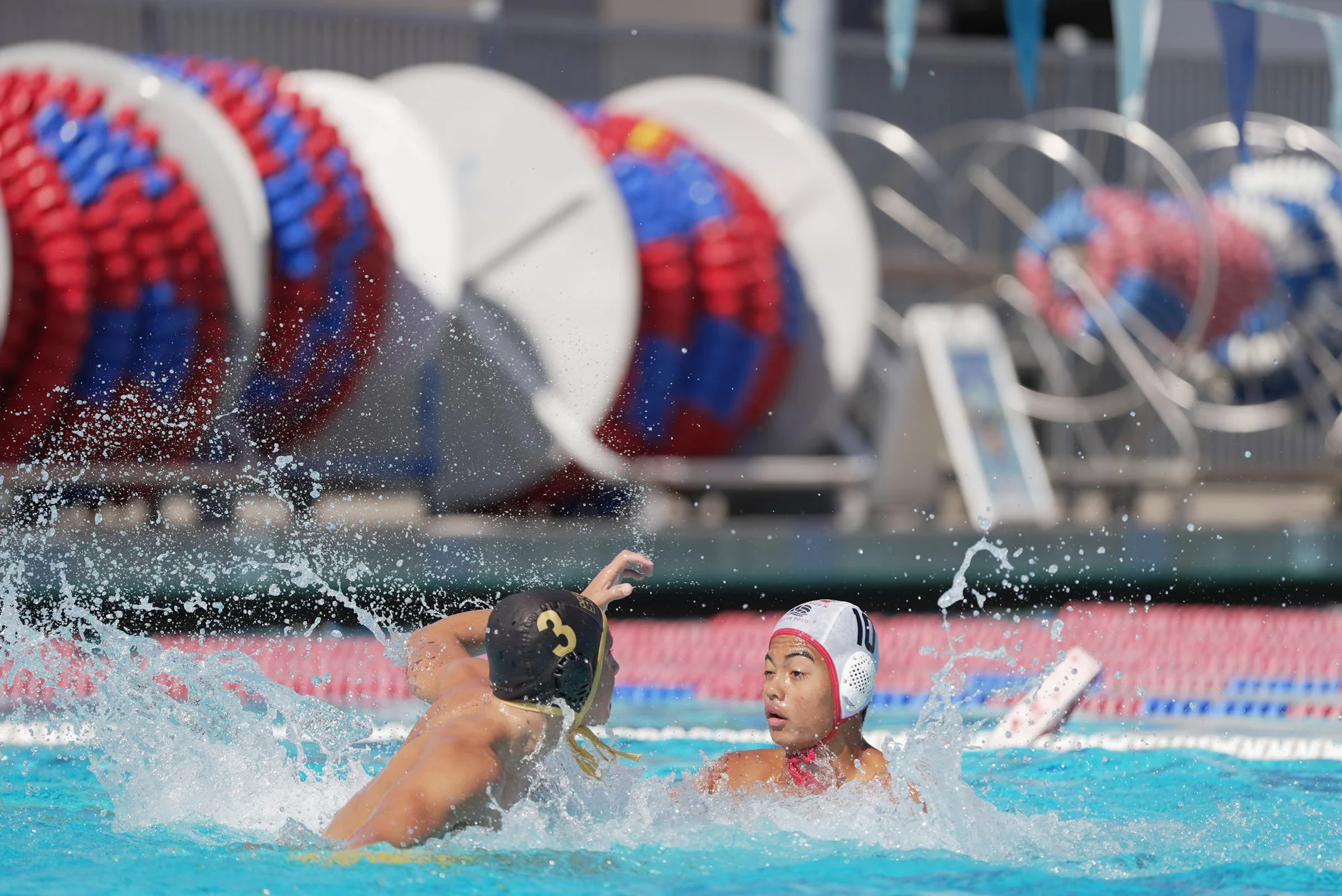 Boys water polo players compete near the lane lines