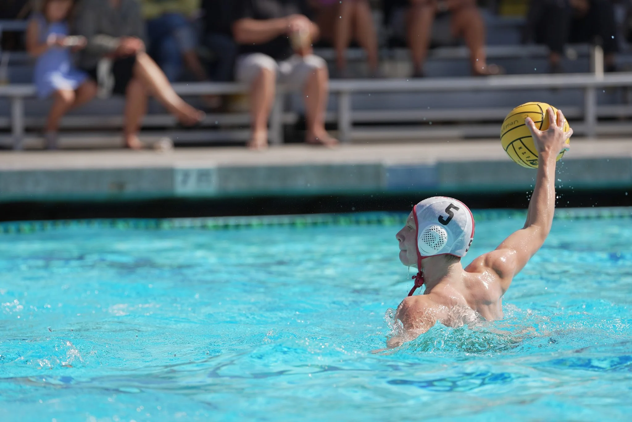 Boys water polo player reaches high with the ball